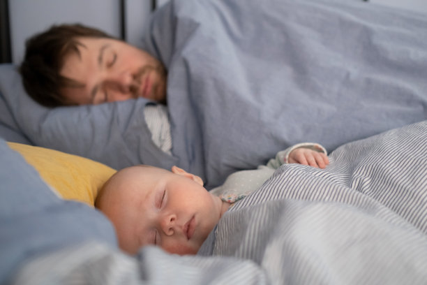 熟睡的父亲和可爱的孩子一起躺在床上。图片下载