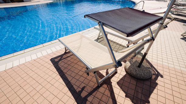 度假村游泳池。夏季度假椅，豪华酒店泳池休闲休息室。海滩懒人的马车。日光浴浴床度假。碧水蓝天，阳光快乐旅游度假。图片下载