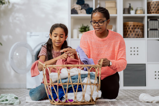 女儿帮助母亲做家务，妇女们把要洗的衣服分类、叠好、准备烘干，她们一起在浴室里笑着聊天图片下载