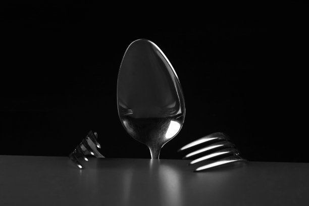 金属勺子和两把叉子组成了概念性的幻想人物。勺子和叉子放在桌子上。图片下载