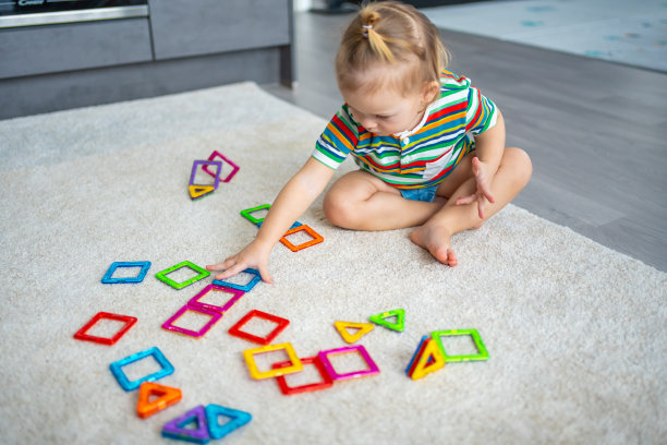 小女孩在家里玩五颜六色的磁铁塑料积木套件。玩教育游戏的孩子。儿童早期发展图片下载