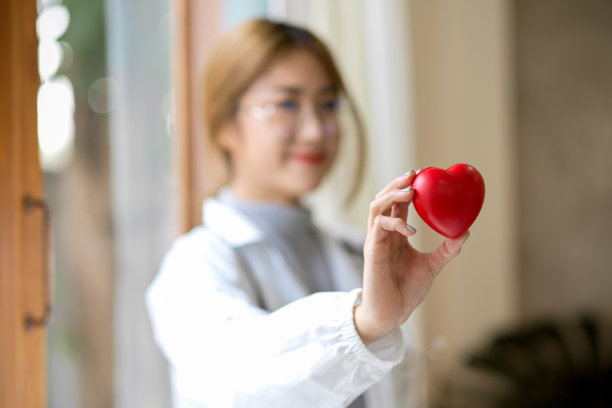 一位身穿白大褂的女医生拿着一个心脏模型。图片下载