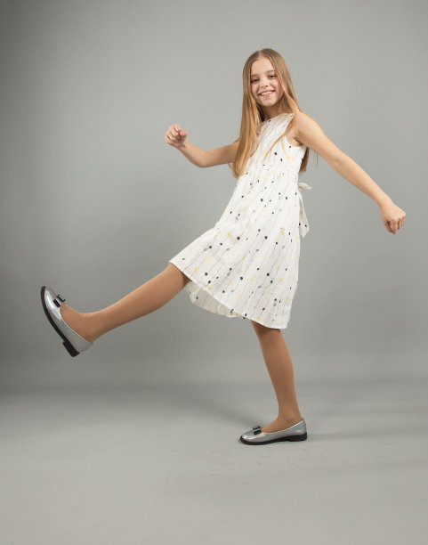 一个漂亮的小女孩，穿着浅色的衣服，走在灰色孤立的背景上。图片下载