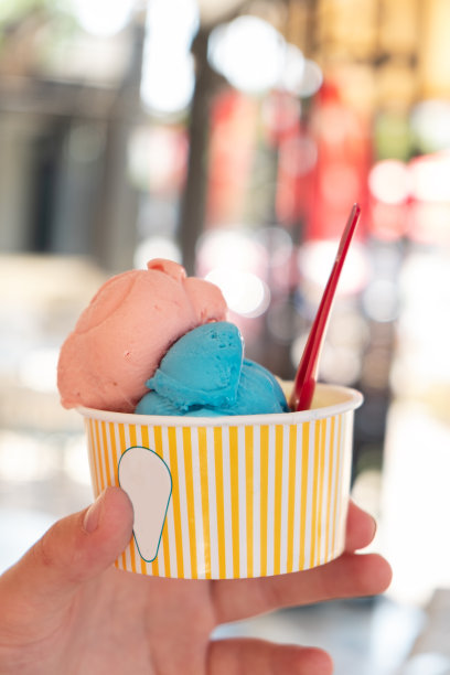 手握纸杯，模糊的背景上放着冰淇淋热天的清爽小吃度假概念垂直照片图片下载