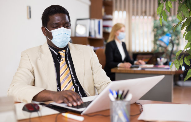 带着防护面罩的商人独自工作，带着笔记本电脑和文件图片下载