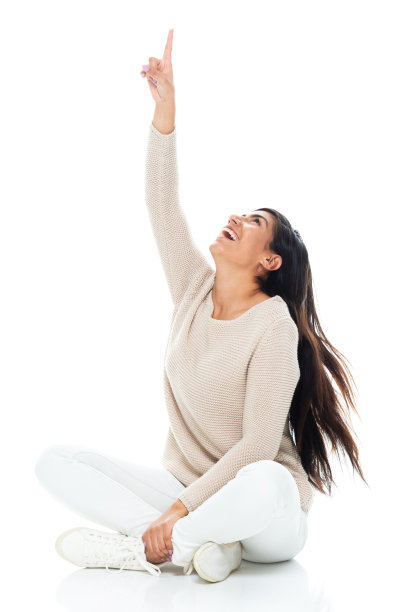 拉丁美洲和西班牙裔的年轻妇女坐在地板前的白色背景，穿着暖和的衣服图片下载