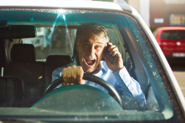 好消息:快乐的中年男子在车里用手机，看起来充满了快乐和幸福图片下载