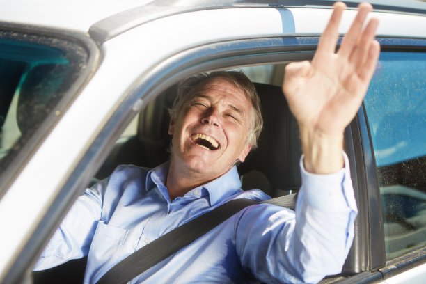 一个快乐的中年男人开着车，对着镜头微笑着挥手图片下载