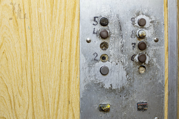 老式电梯按钮带有封闭电梯轴门，前后背景模糊带有散景效果图片下载