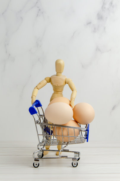 木制人体模型和一篮子鸡蛋。复活节准备理念，杂货店购物，农作支持图片下载