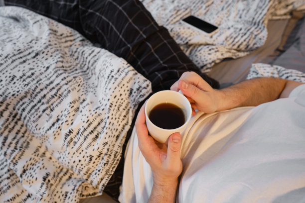 男人手中的一杯茶或咖啡。一个男人在早上喝热茶。享受家的舒适。一个男人手中白色杯子的特写图片下载