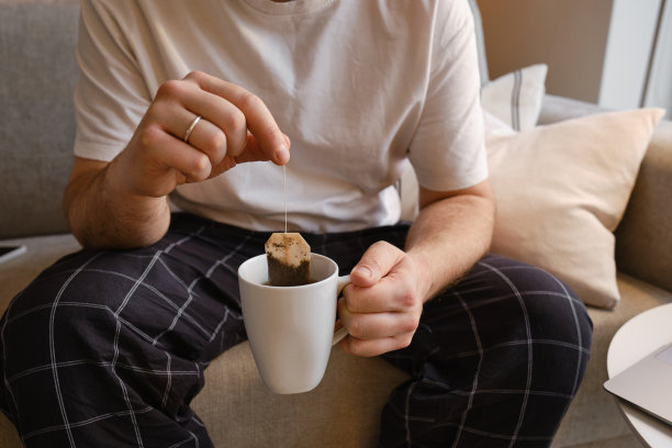 男人手中的一杯茶或咖啡。一个男人在早上喝热茶。享受家的舒适。一个男人手中白色杯子的特写图片下载