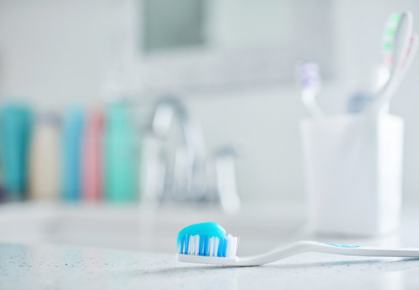 现代浴室的塑料牙刷，在塑料牙刷架前放上牙膏图片下载