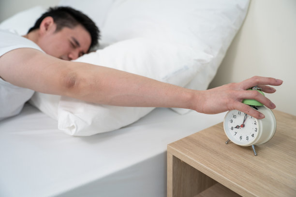 亚洲有魅力的年轻人关掉早上的闹钟。帅男觉得懒，累了躺在舒适的床上，在卧室里无视噪音，继续睡觉不想醒来。图片下载