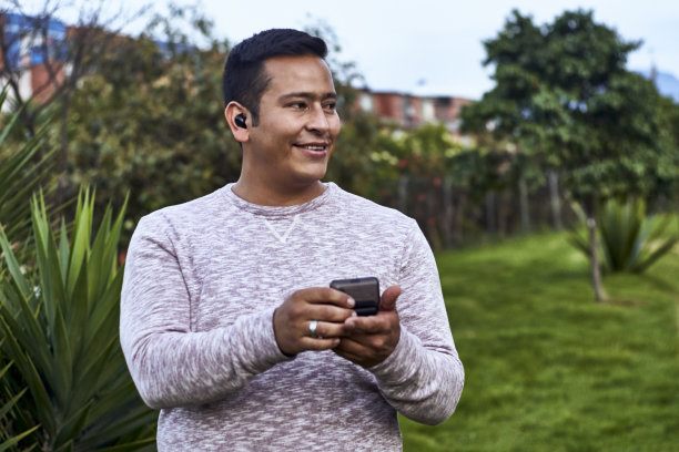 傍晚的灯光下，一个男人戴着新的无线耳机站在城市的郊区图片下载