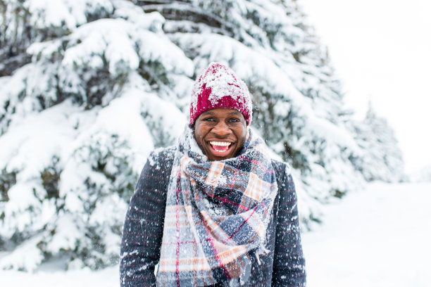非裔美国人英俊的男子，戴着红帽子，穿着时髦的格子呢外套，露出雪白的微笑看着镜头在公园外图片下载
