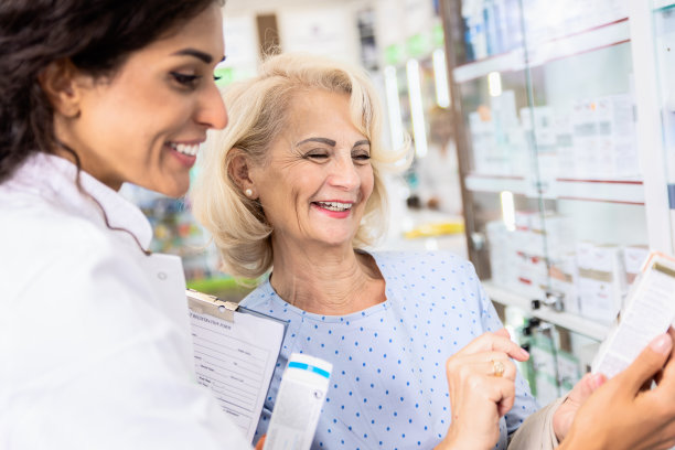 药剂师在药店向高级女性顾客销售药品。图片下载