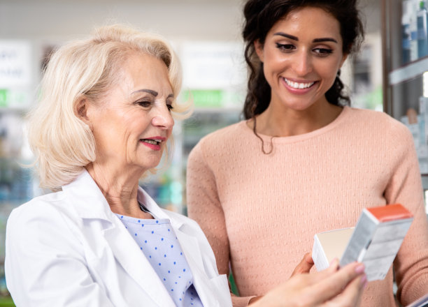 高级药剂师在药店向年轻女性顾客销售药品。图片下载