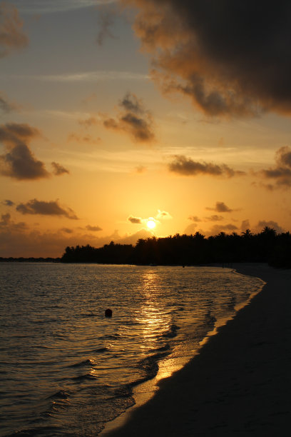 马尔代夫美丽的日落。白色的沙滩，平静的大海，橘黄色的天空和白云。图片下载