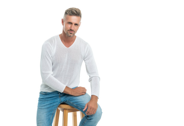 面带微笑的英俊成熟的灰发男子坐在椅子上孤立的白色，男人的美丽。图片下载
