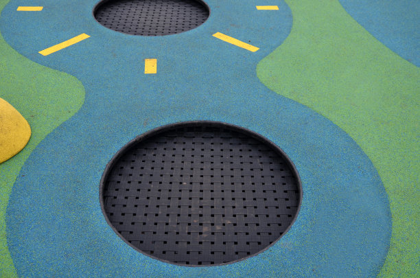 操场的白色橡胶表面上有黄色的球和彩色的斑点在霜冻的人类脚印。凸起的镜头，如球，木凳和圆形的蹦床沉入地形。图片下载