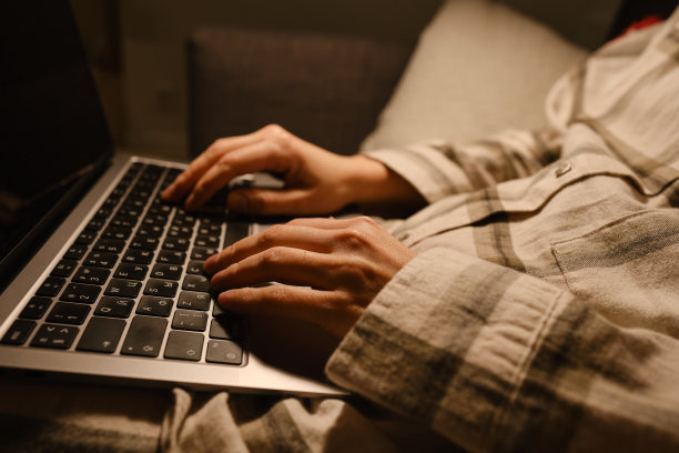 女孩在家里或酒店的床上用笔记本电脑和智能手机工作。遥远的工作。在家办公。卧室里的女人正在笔记本电脑上打字，为学生进行远程教育，上网图片下载