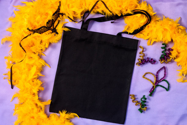 Mardi Gras Mockup黑色大手提袋与闪光装饰和嘉年华面具在织物丁香色背景图片下载
