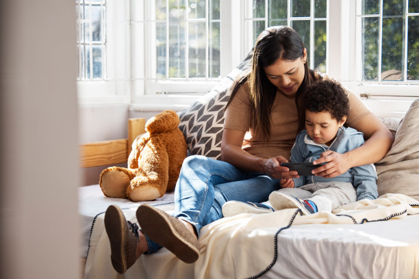 这张照片拍摄的是一对年轻的母亲和儿子在家里玩手机图片下载