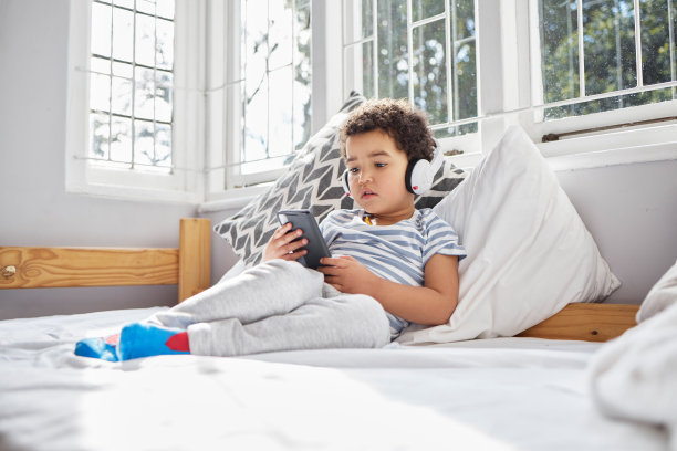 一个小男孩戴着耳机在家里打电话的照片图片下载