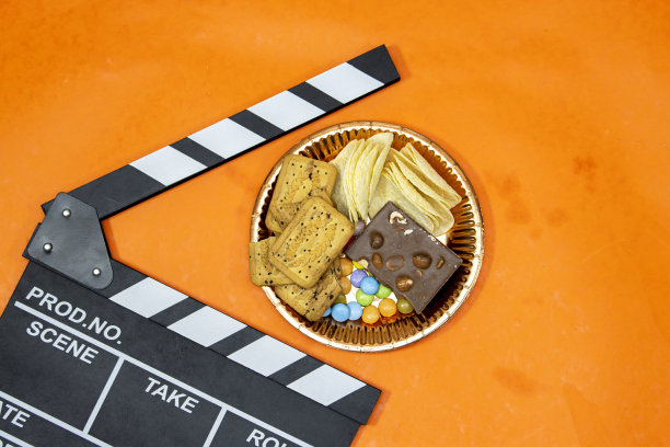 影楼的拍板。电影制作拍板、板岩片。视频直播巧克力糖果和巧克力棒与橙色背景上的糖果图片下载