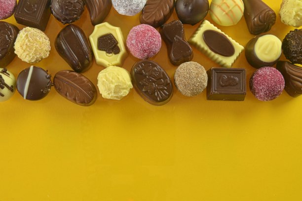 巧克力饼干和果仁糖为节日活动黄色背景与大复印空间。平躺图片下载