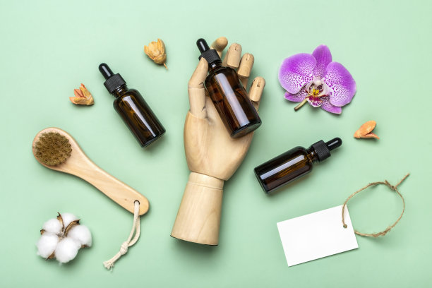 木制手握玻璃化妆品瓶，粉红色兰花孤立在绿色背景俯视图平铺生态，零浪费，有机产品概念复制空间图片下载