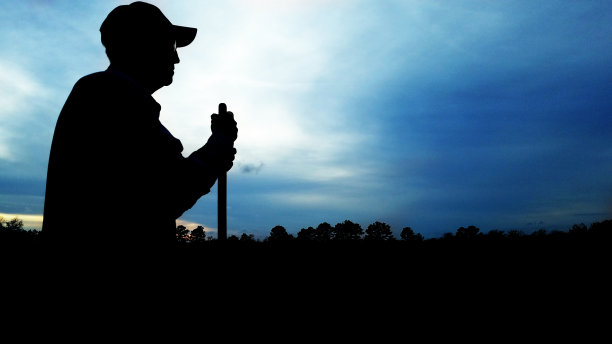一位年长的农民停下脚步，欣赏着他农田上的夕阳。图片下载