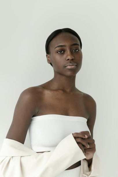 腰部以上的肖像美丽的年轻非洲女孩穿着白色露脐上衣和裤子在白色背景摆姿势图片下载