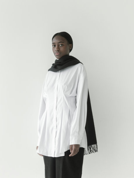 肖像美丽的年轻非洲女孩穿着白色的裙子，黑色的裤子和黑色的围巾摆姿势在白色的背景图片下载