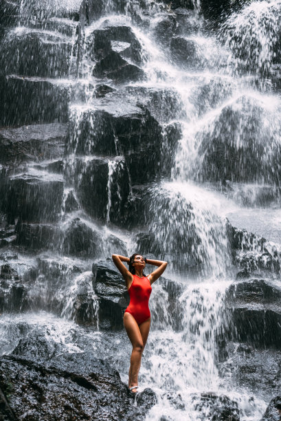 美丽的女孩在瀑布上的巴厘岛印度尼西亚。瀑布边的性感女孩。年轻美丽的女孩在比基尼在瀑布洗澡。本空间图片下载