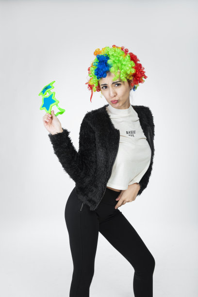 女孩戴着五颜六色的卷发假发，大而华丽的眼镜，做出有趣的面部表情。图片下载