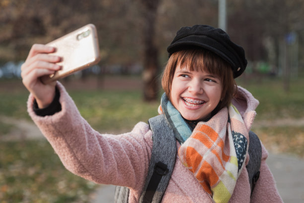 戴着牙套的快乐女学生在户外自拍图片下载