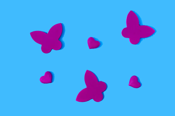 蓝色背景上的洋红色蝴蝶和心。情人节横幅或卡片的创意概念。最小的艺术设计。平躺图片下载