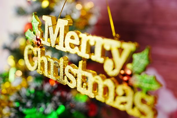 一个金色的圣诞快乐装饰标志，背景是一棵装饰过的圣诞树图片下载