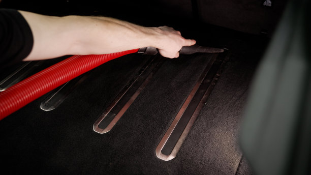 专业男性工人用专业提取方法和吸尘器对汽车后备箱进行干洗的双手。洗车和清洁。主人用吸尘器清扫了汽车的后备箱图片下载