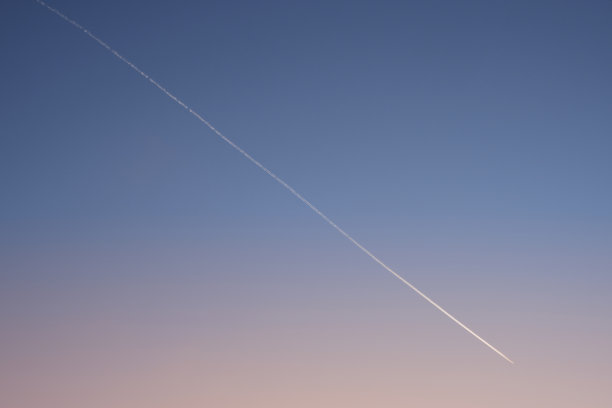 日落后清晰的渐变夜空上的白色斜对角飞行器轨迹。飞机跟踪。图片下载