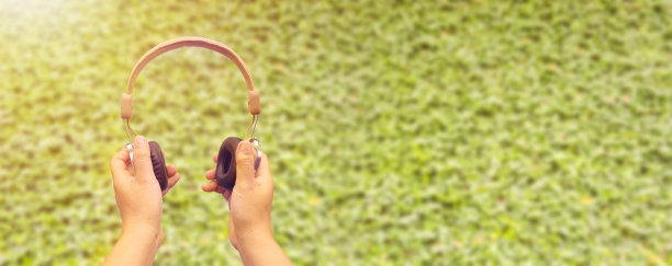 手拿耳机贴在绿色的墙上图片下载