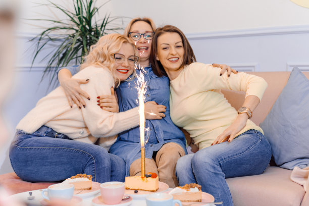 快乐的朋友用庆祝蛋糕庆祝生日，一群快乐的人在甜点上点燃烟花，祝生日快乐，蜡烛，在家里或咖啡馆庆祝图片下载