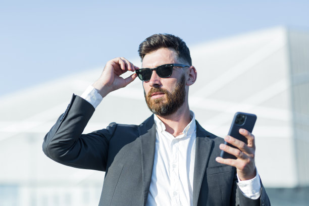 一个留着胡子、戴着墨镜的成功商人的特写照片，一个男人在办公室外面用电话图片下载