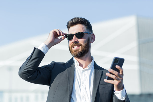 一个留着胡子、戴着墨镜的成功商人的特写照片，一个男人在办公室外面用电话图片下载