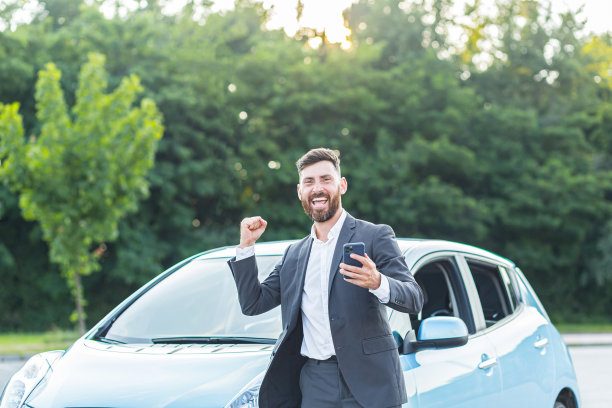 成功的商人在胜利的喜悦中，在手机应用程序中赢得汽车，看着手机，发出喜悦和幸福的呼喊图片下载