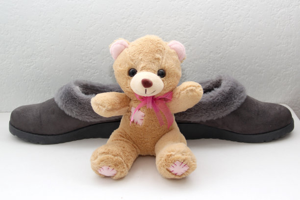 舒适的灰色毛绒拖鞋准备休息，上床睡觉旁边的泰迪熊放松和放松图片下载