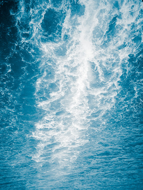 一个白色的波浪和泡沫在蓝色的水，从船发散的轨迹图片下载