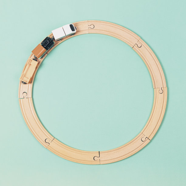 玩具火车在浅绿色的背景下绕着木制铁路行驶。俯视图图片下载